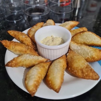 Porção de pastéis com molho no centro